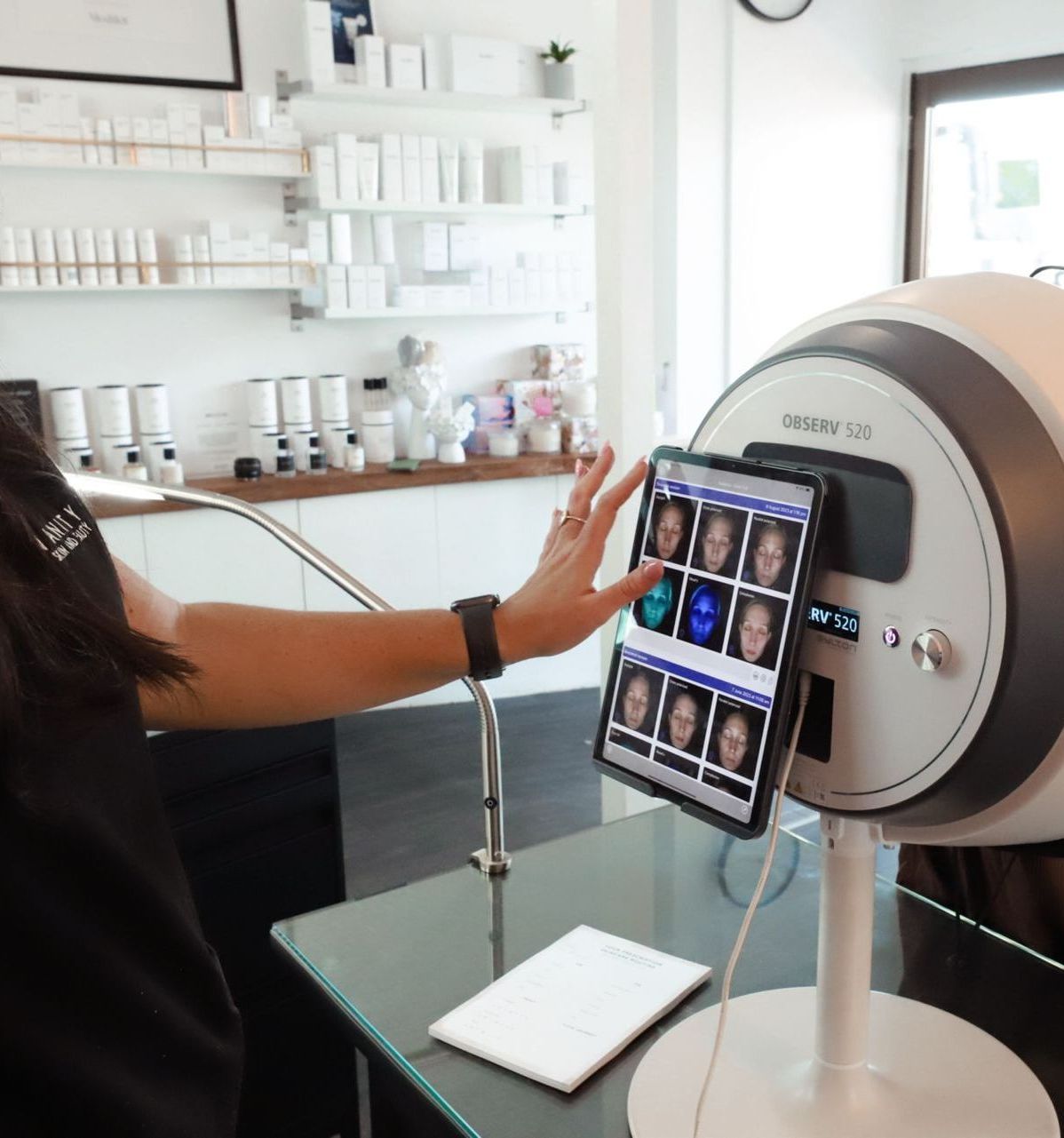 A woman is using a tablet to look at her face — Vanity Skin and Beauty Forster in Taree, NSW