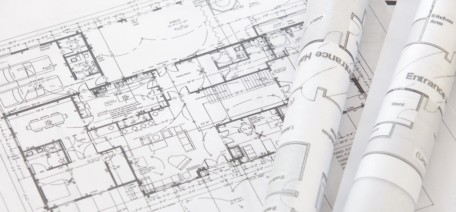 Un plan architectural détaillé déroulé à plat, avec des rouleaux supplémentaires de plans d'étage à proximité.