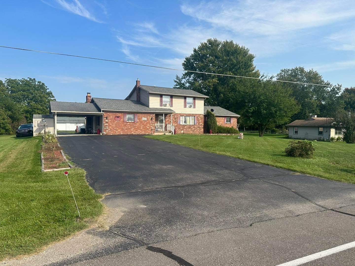 Suburban house with a large driveway, garage, and lawn under a clear blue sky