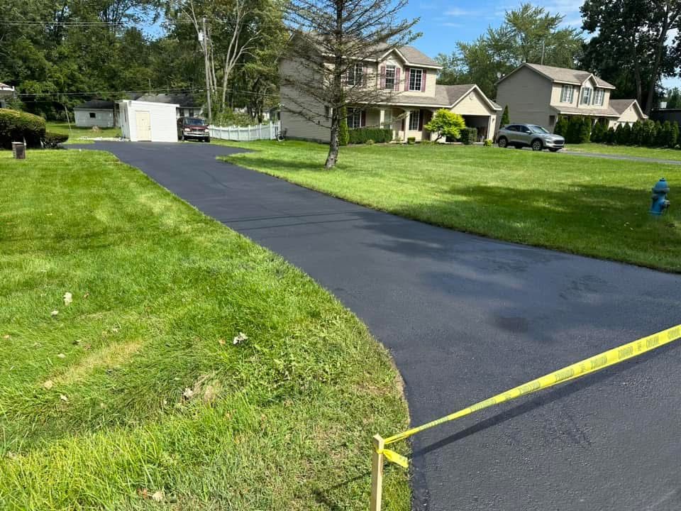 Fresh black asphalt driveway in a suburban neighborhood with a yellow barrier tape across the entrance