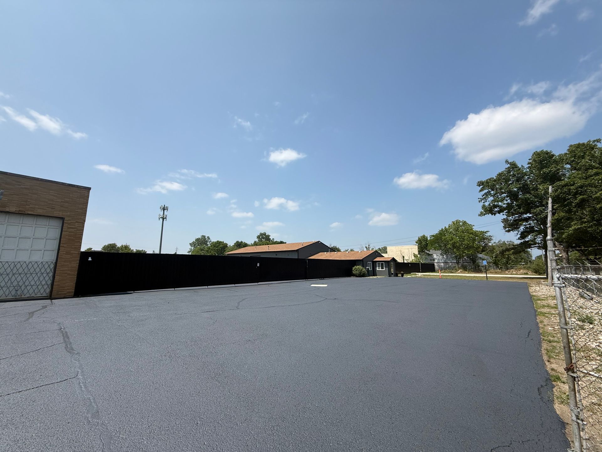 Empty gravel parking lot beside a brick building under a blue sky