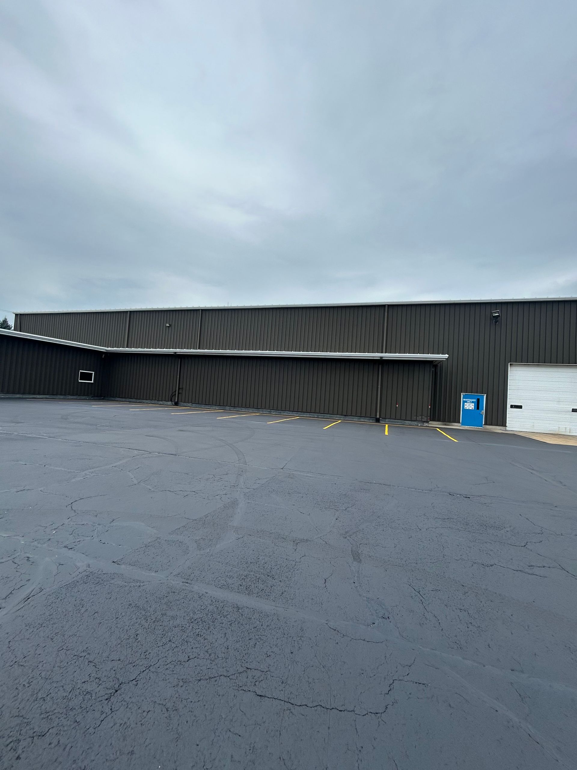 Storm-damaged black warehouse siding with a partially collapsed wall under a gray sky