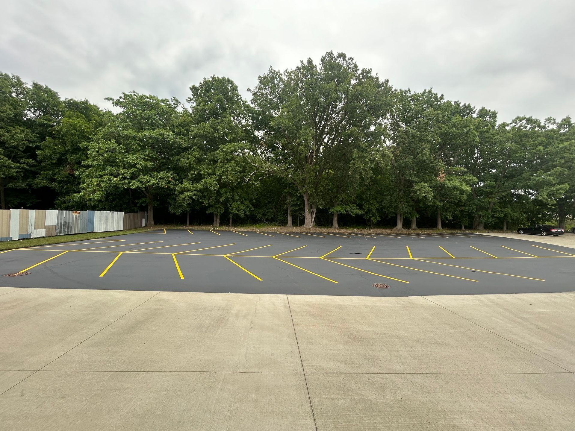 Empty paved parking lot with yellow markings and trees in the background