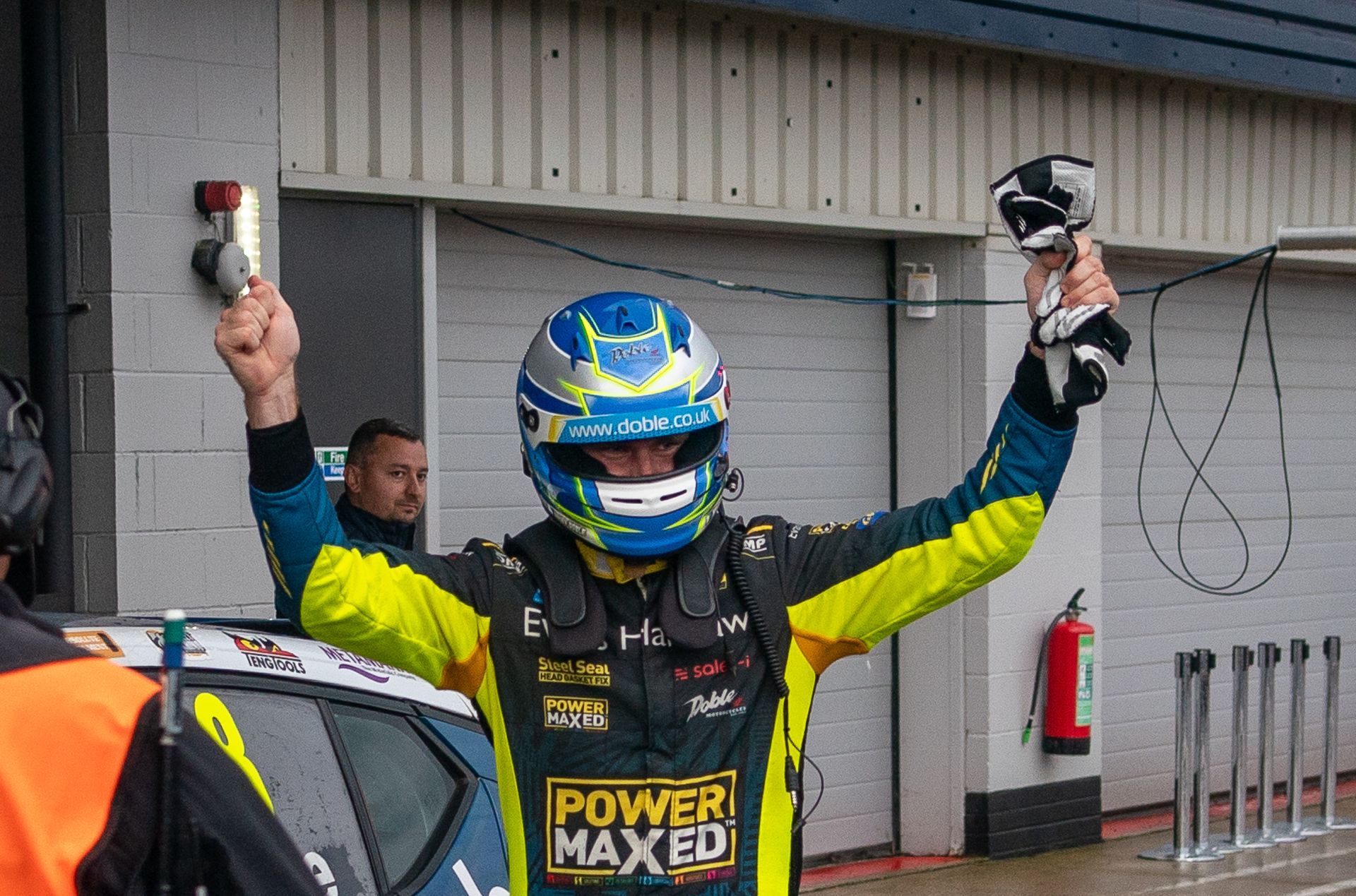 A man wearing a helmet and a power maxed shirt is holding up his arms.