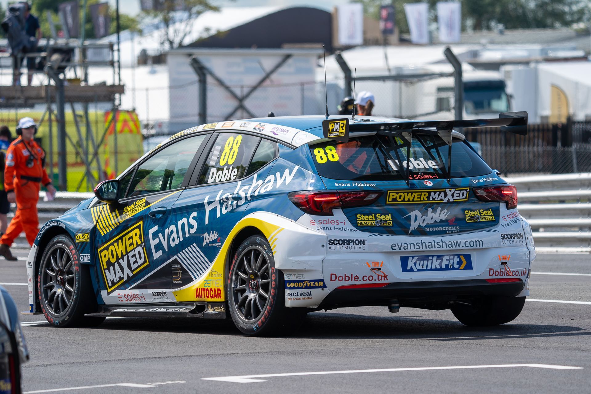 A blue and yellow race car is parked on the side of the road.