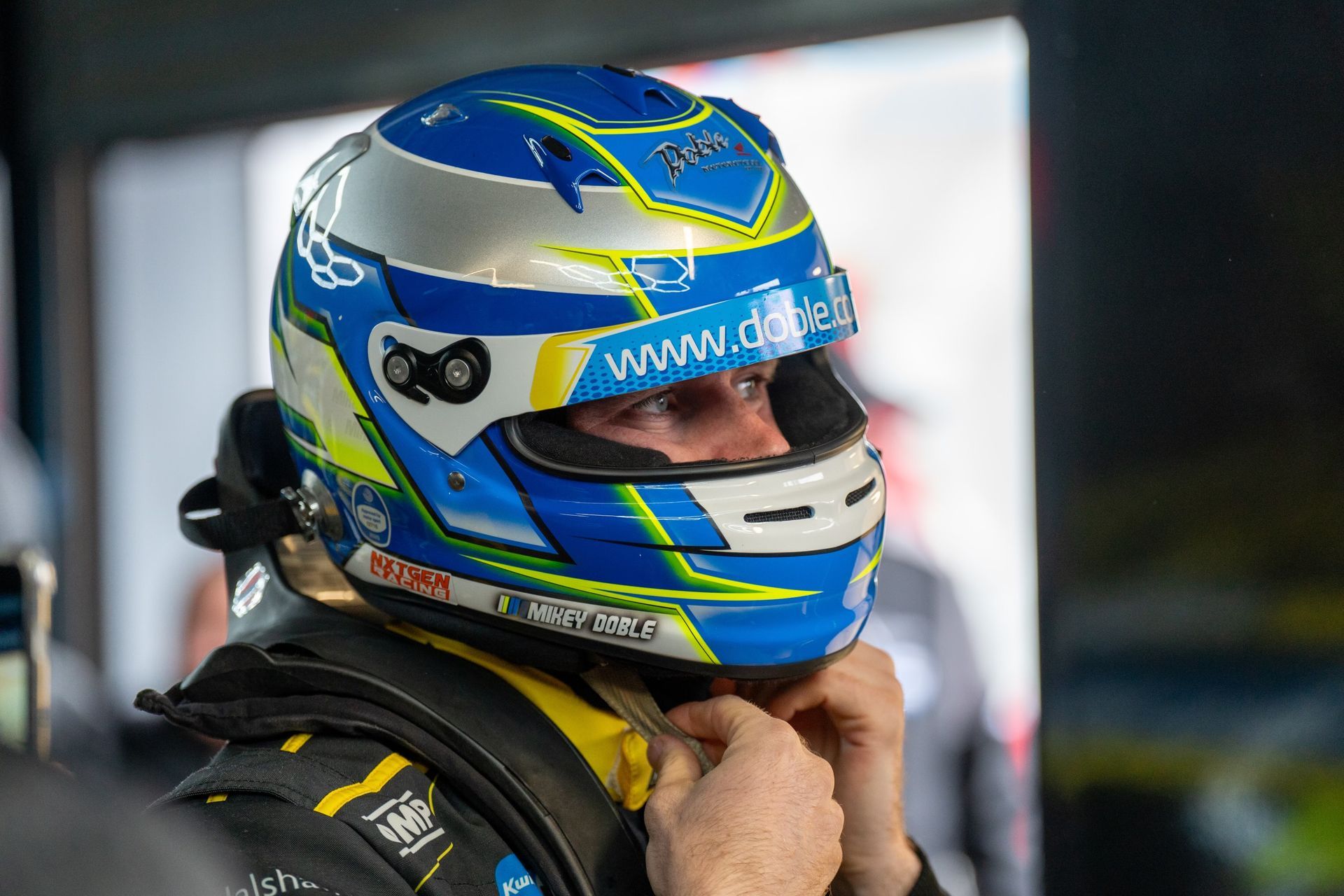 A man is putting on a blue and yellow helmet.