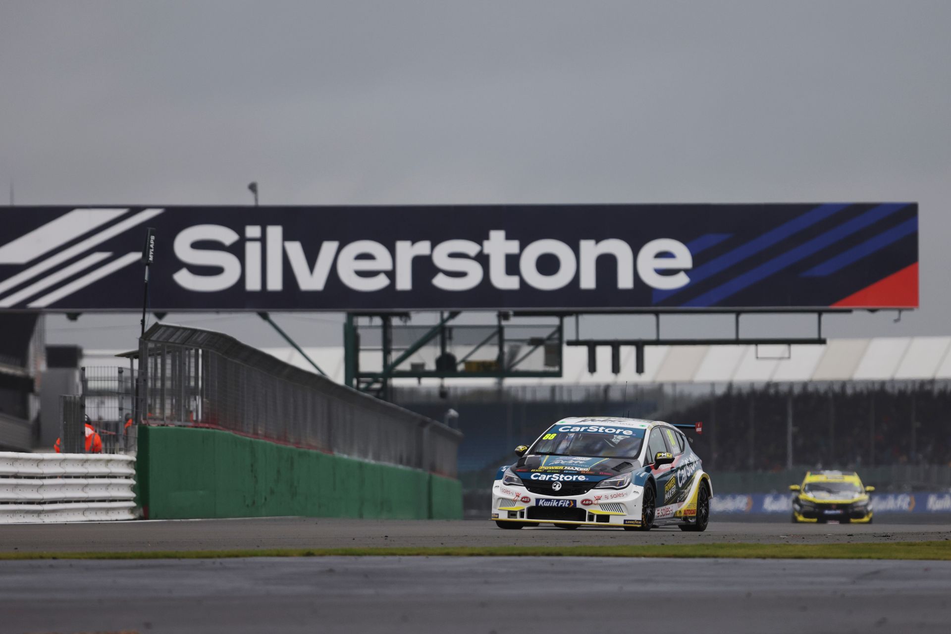 A race car is driving down a track in front of a silverstone sign.