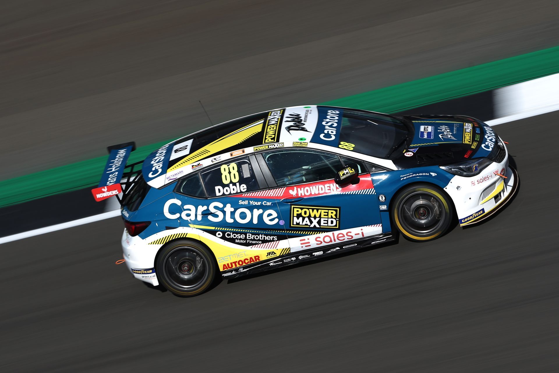 A blue and white race car is driving down a race track.