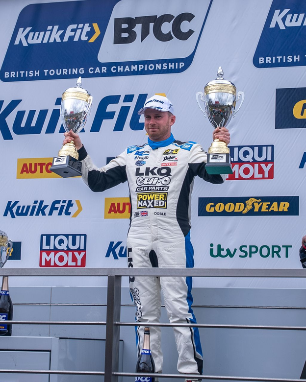 A man in a car store uniform is holding a trophy