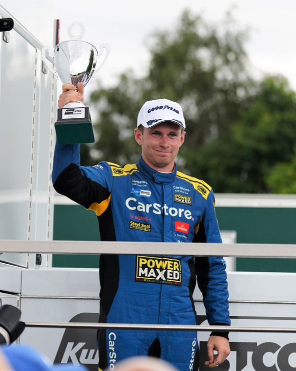 A man is holding a trophy in front of a crowd of people.