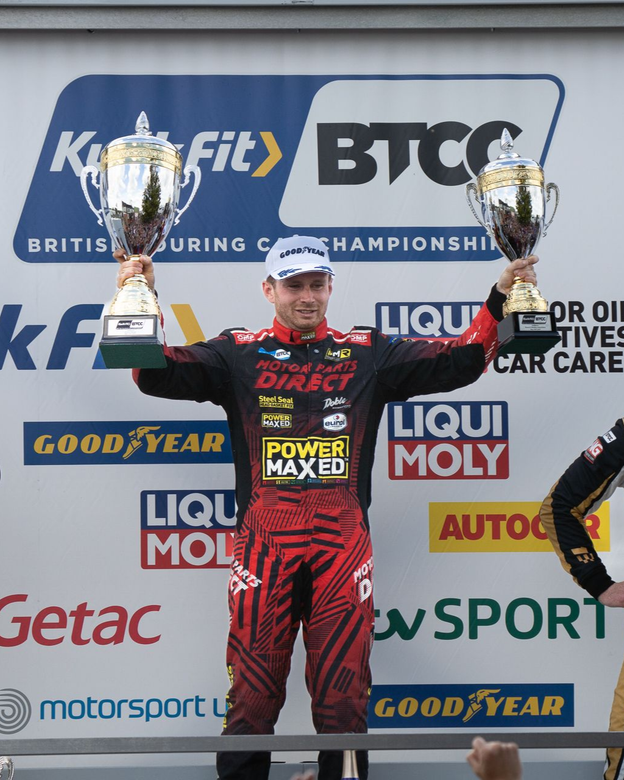 A man in a power maxed shirt is holding a trophy