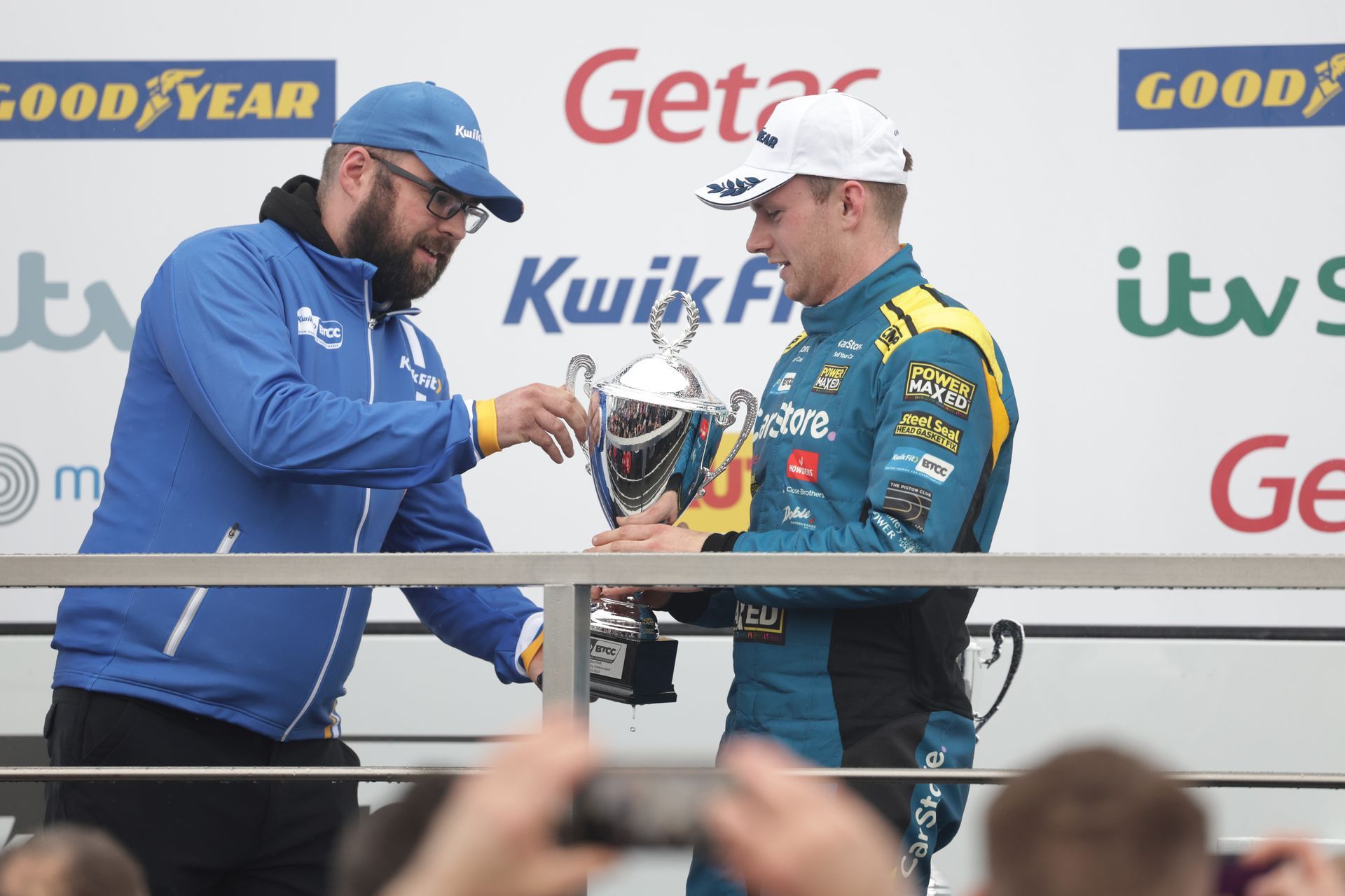 Two men are standing next to each other holding a trophy.