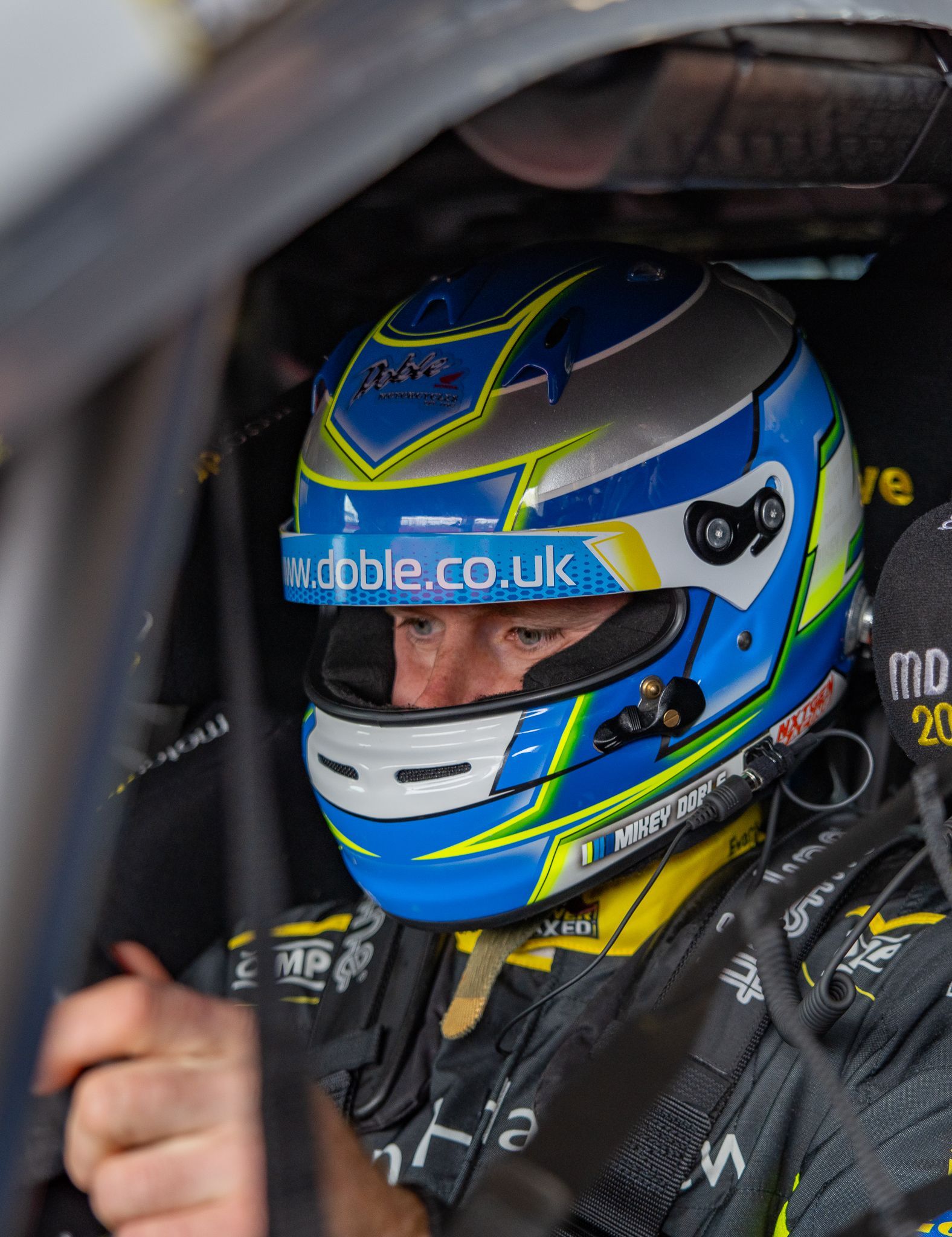 A man wearing a blue and yellow helmet is sitting in a car.