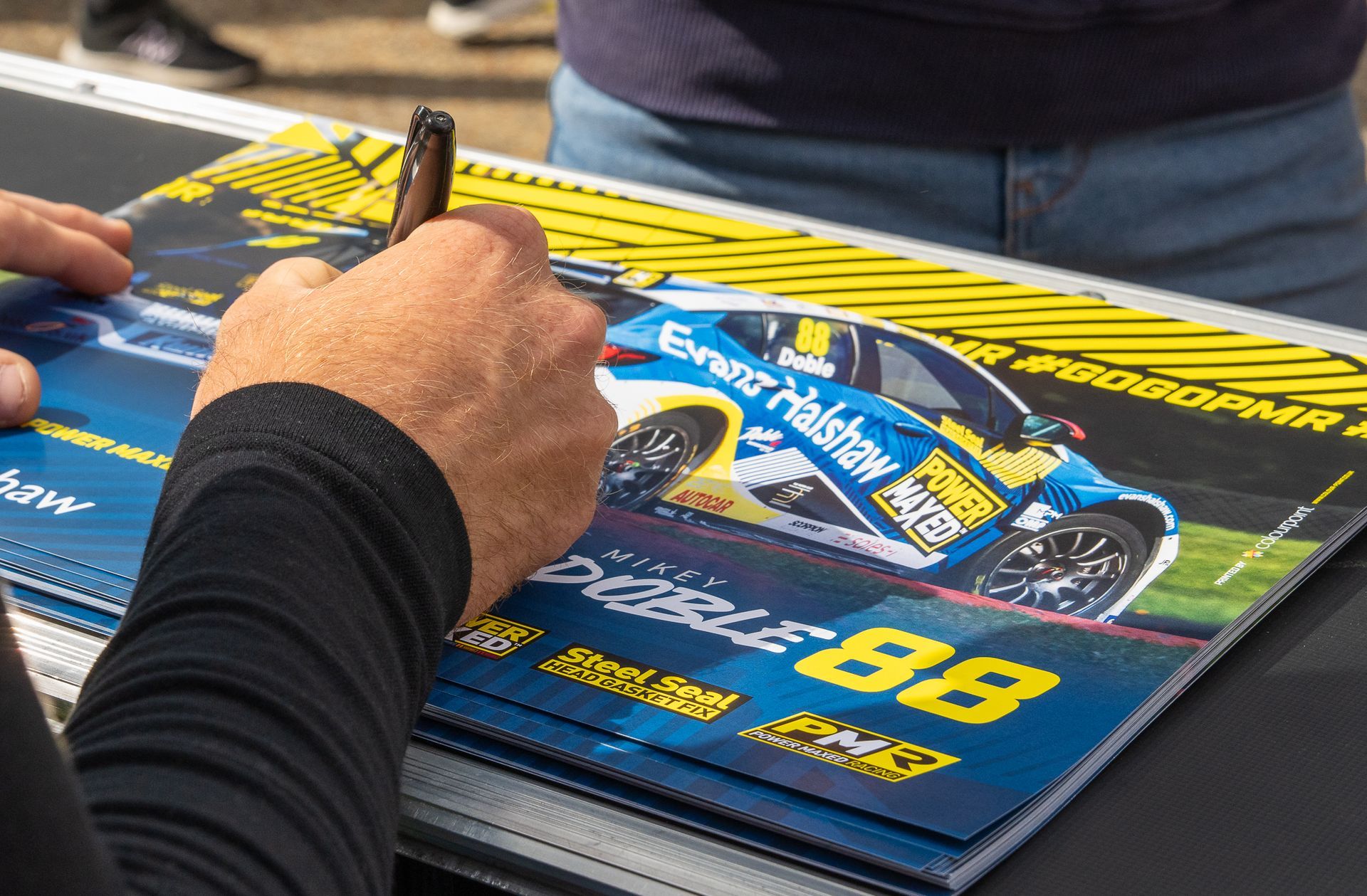 A person is signing a picture of a race car with a pen.