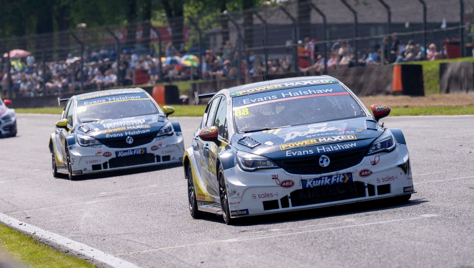 Two racing cars are driving down a race track.