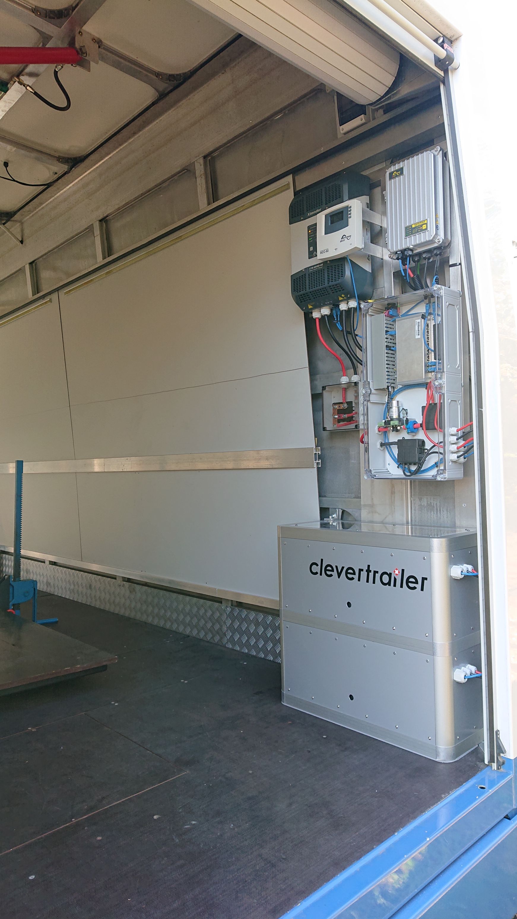 Das Innere eines Anhängers mit einem installierten elektrischen Schaltschrank und einer metallischen Batterieeinheit an der Seitenwand.