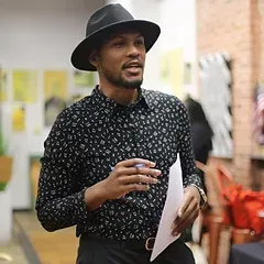 A man wearing a hat and a black shirt is holding a piece of paper.