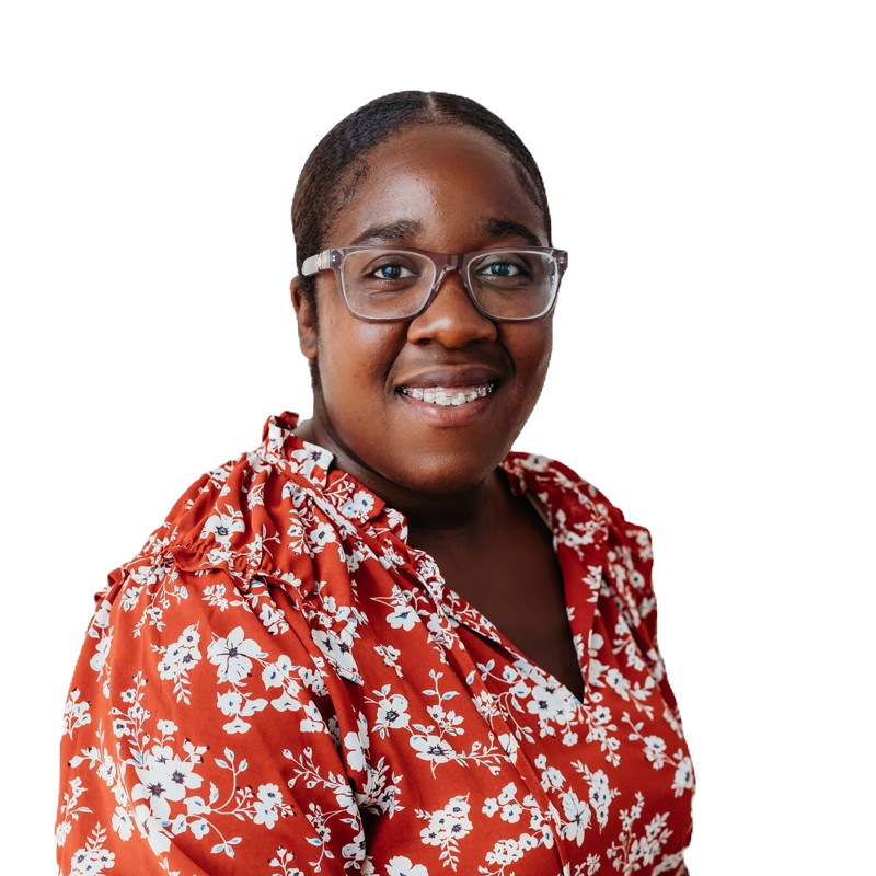 A woman wearing glasses and a red floral shirt is smiling.
