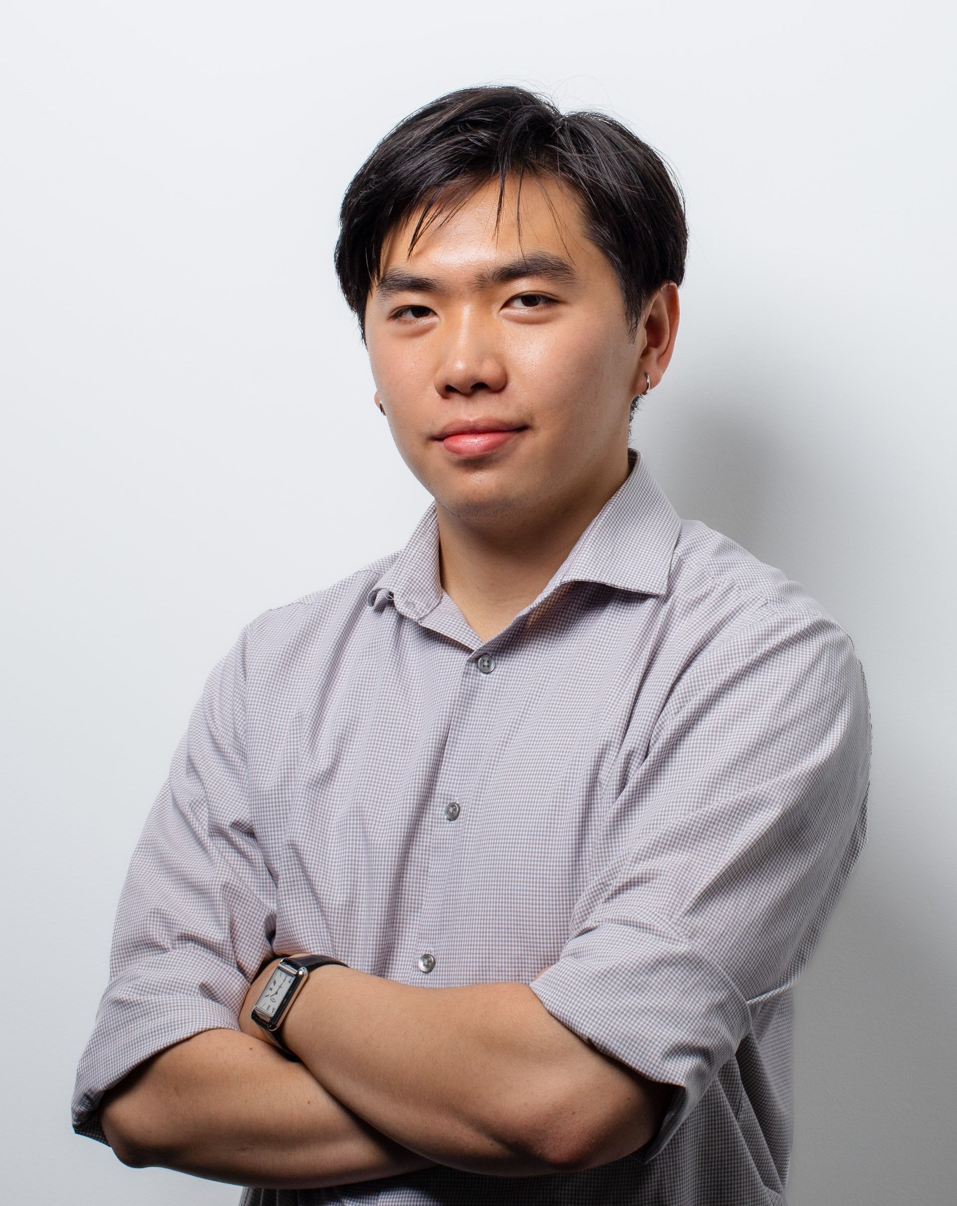A man in a striped shirt is standing with his arms crossed.