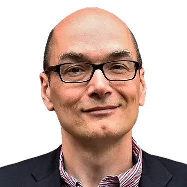 A bald man wearing glasses and a suit is smiling.