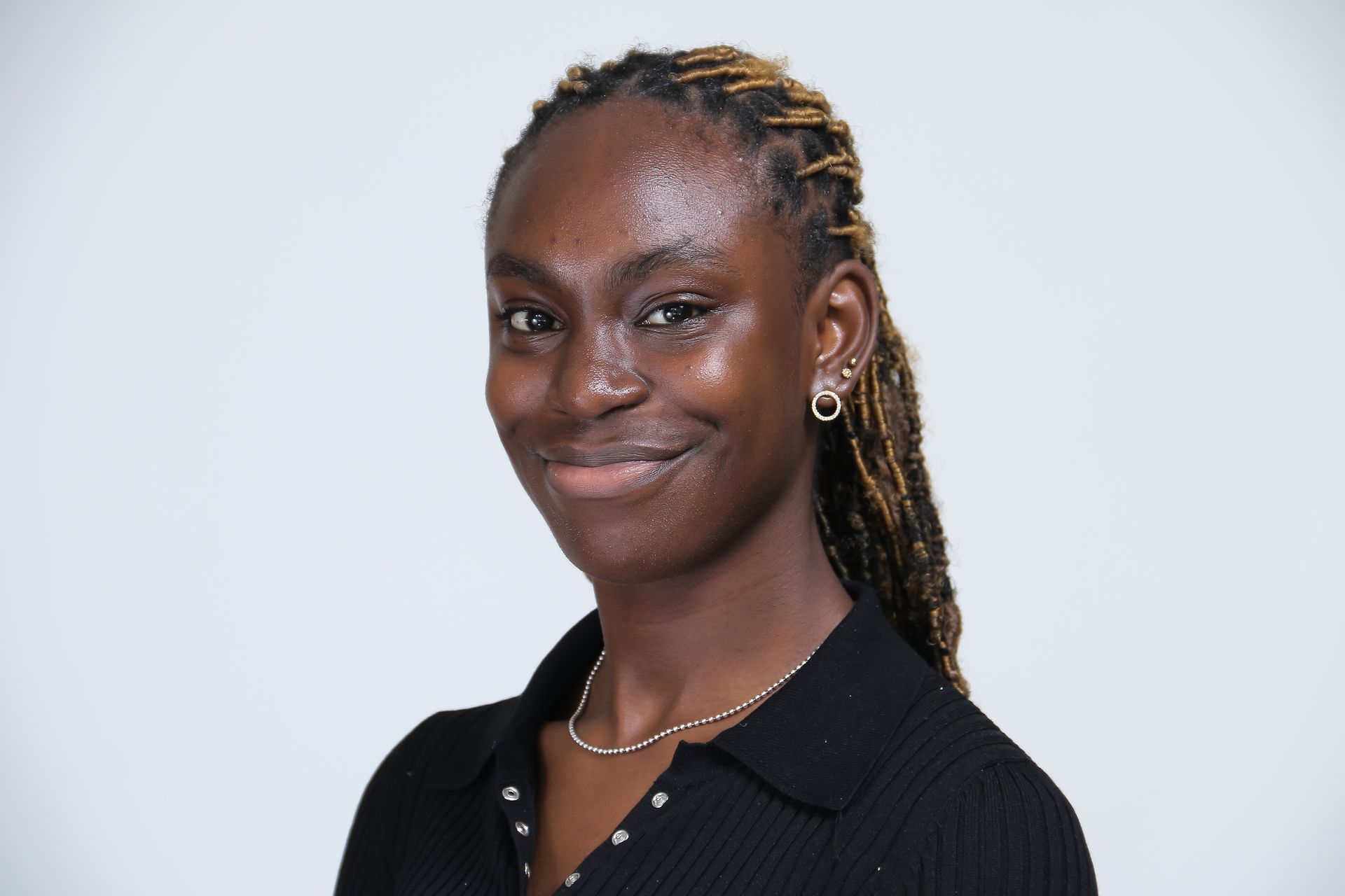 A woman wearing a black shirt and earrings is smiling for the camera.