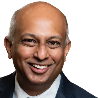 A bald man in a suit and tie is smiling for the camera.