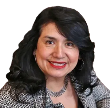 A woman with long black hair is smiling and wearing a necklace and earrings.