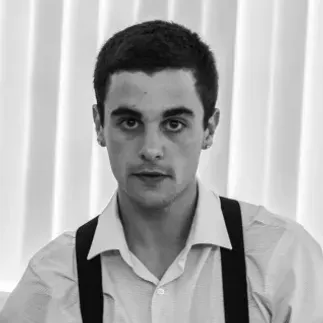 A black and white photo of a young man wearing suspenders and a white shirt.