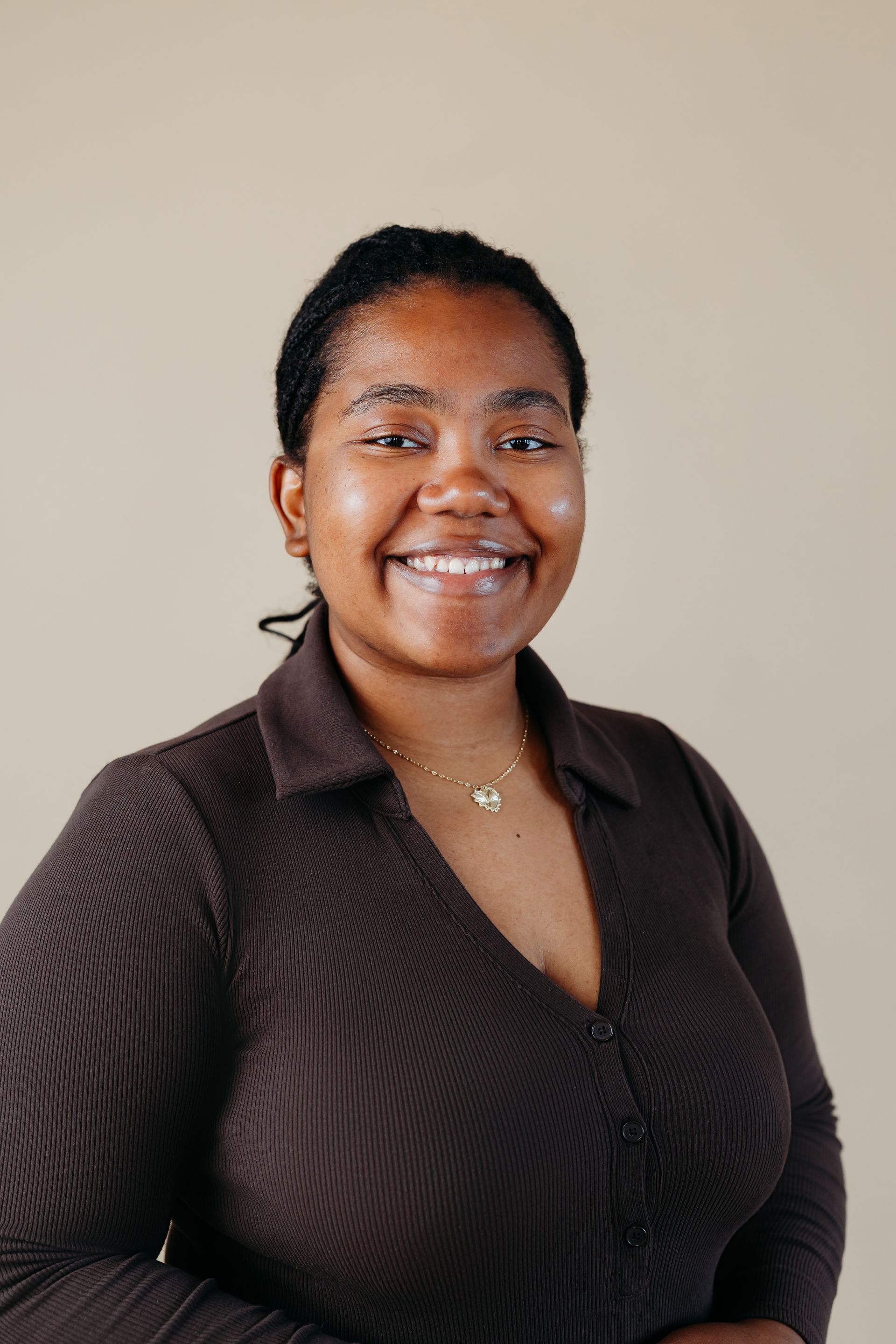 A woman in a brown shirt is smiling for the camera.