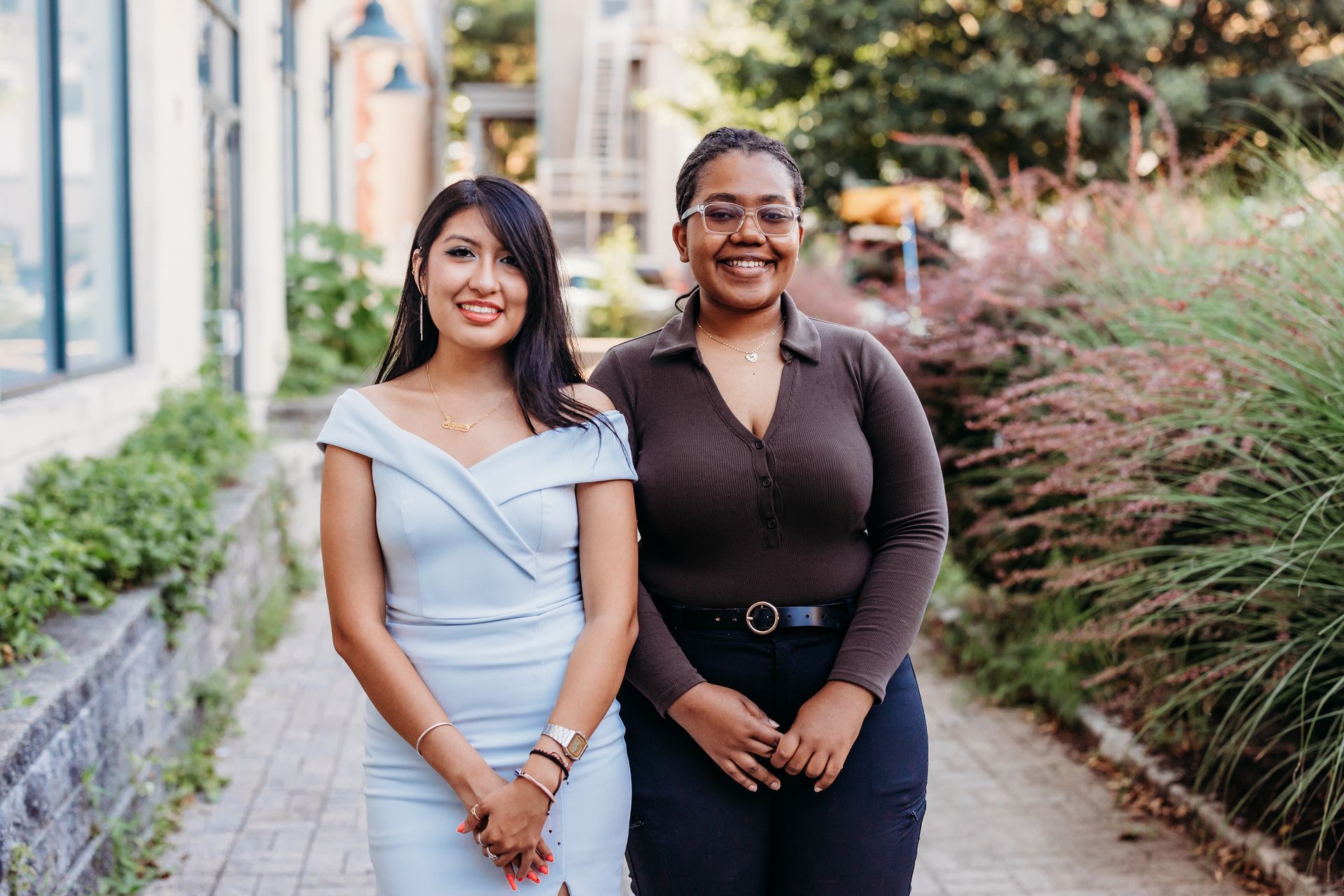 Two women are standing next to each other on a sidewalk.
