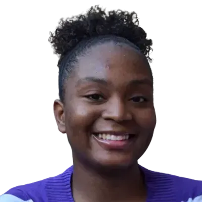 A woman with curly hair is smiling and wearing a purple sweater.