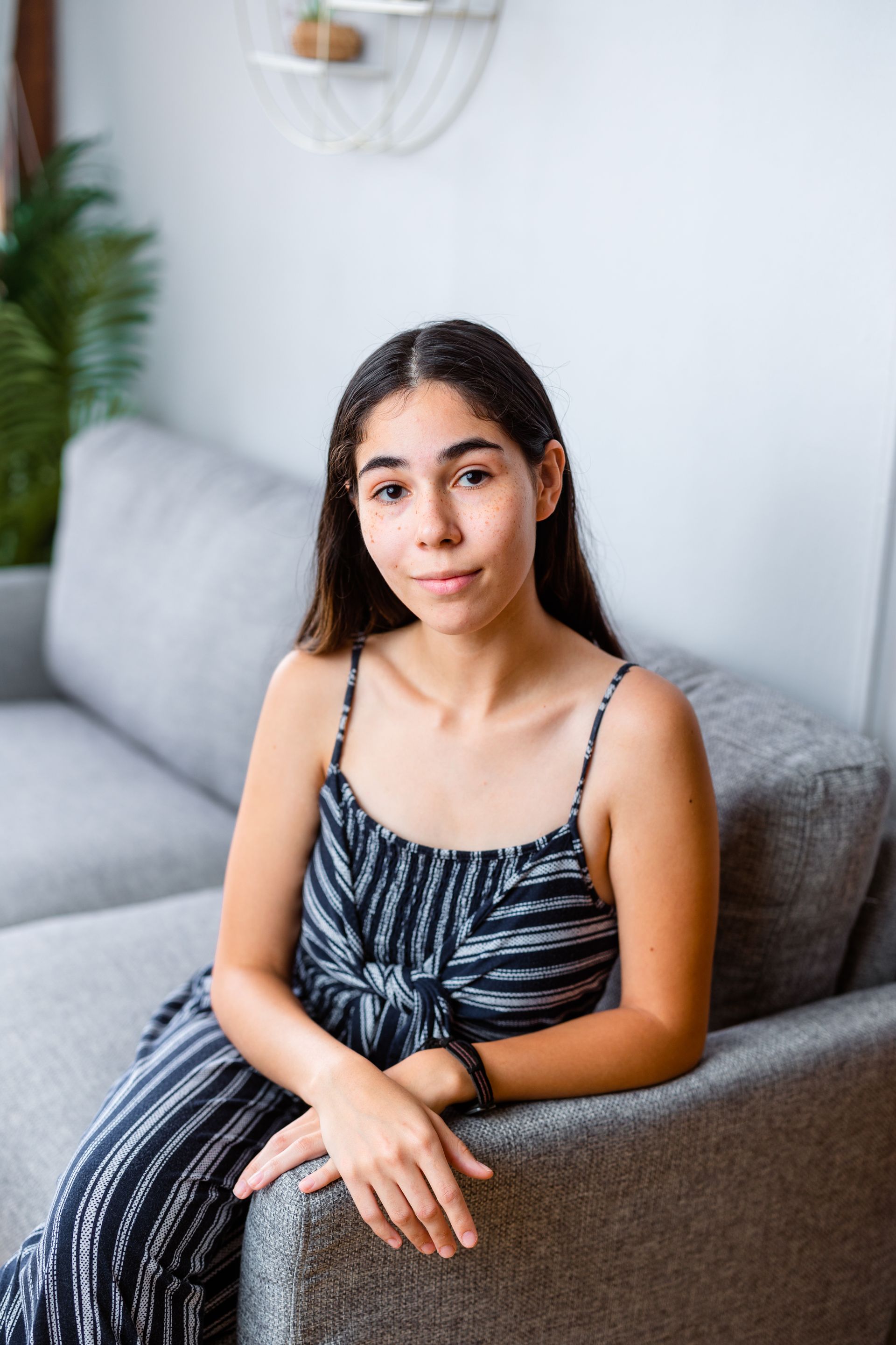 A young woman is sitting on a couch in a living room.