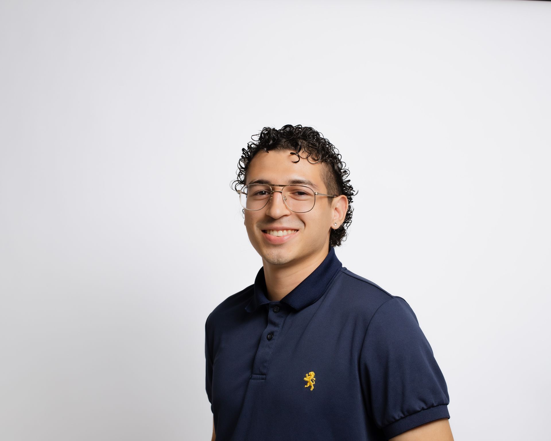 A young man wearing glasses and a blue polo shirt is smiling for the camera.
