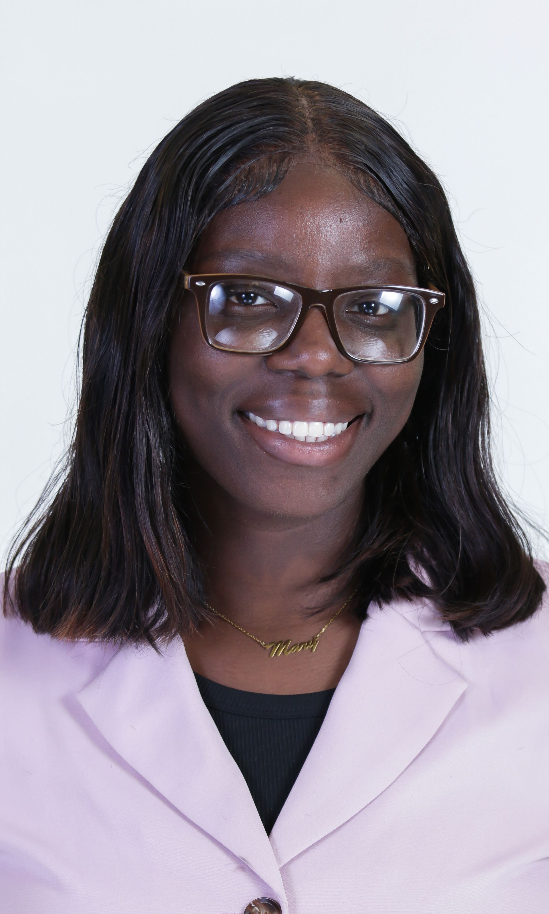 A woman wearing glasses and a pink jacket is smiling for the camera.
