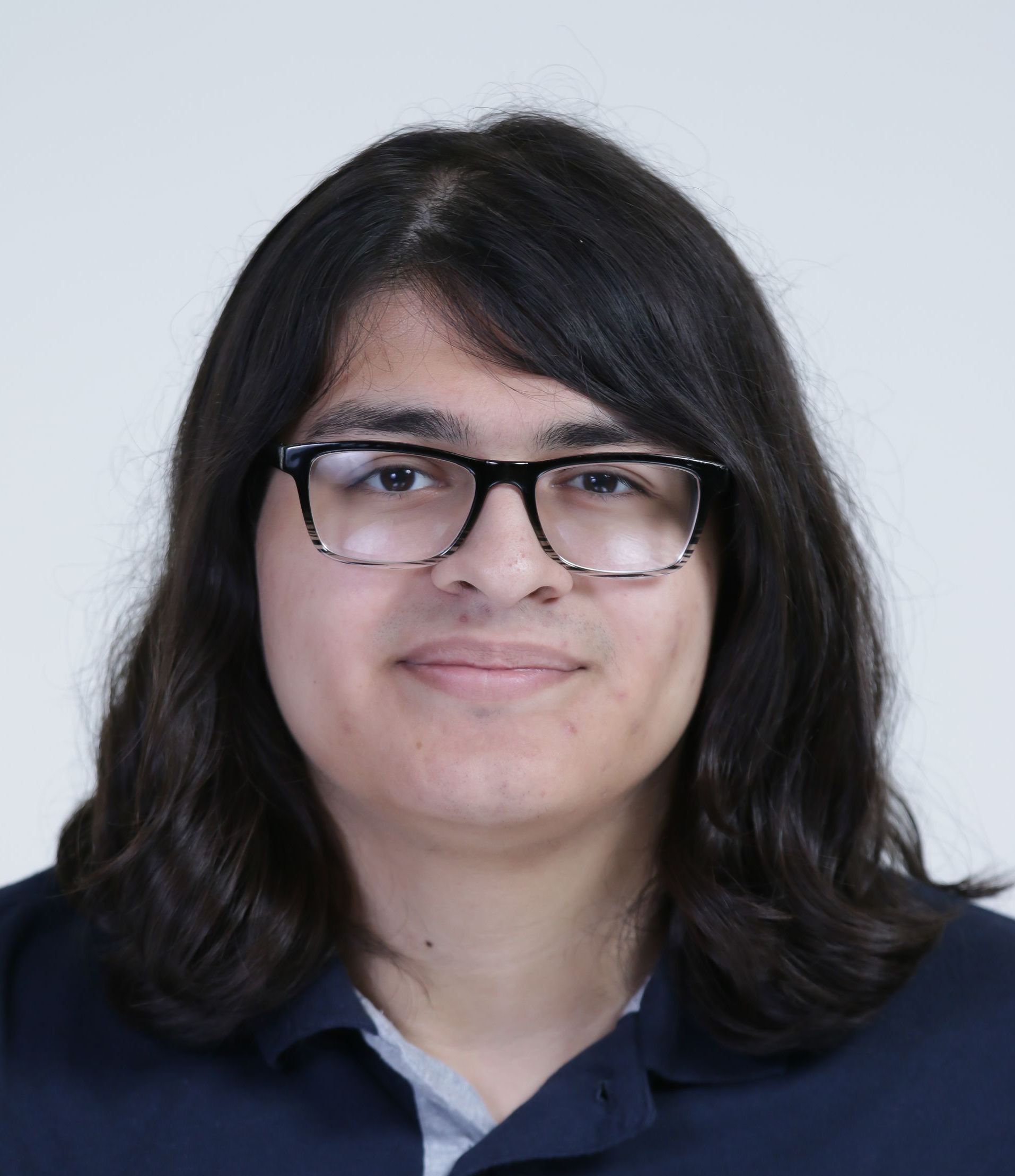 A woman wearing glasses and a blue shirt is smiling