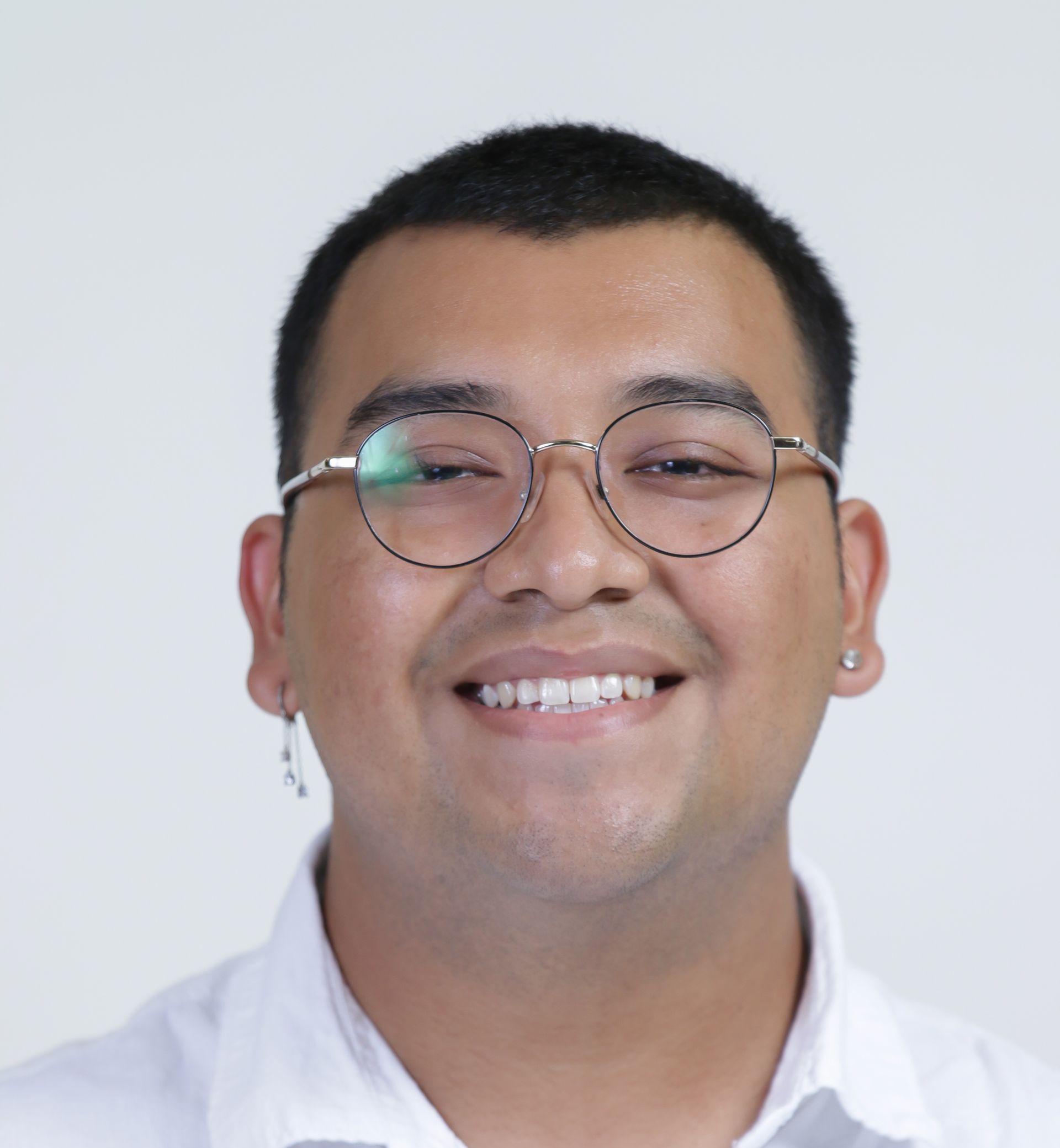 A man wearing glasses and a white shirt is smiling