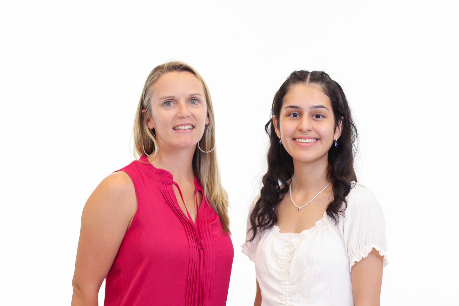 Two women are standing next to each other on a white background.