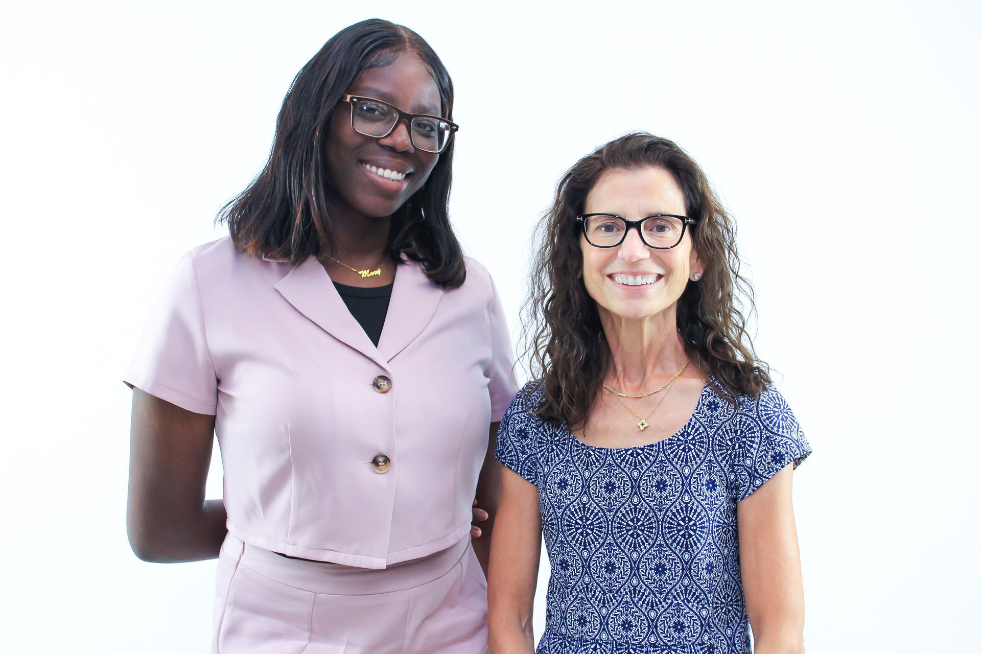 Two women are standing next to each other and smiling for the camera.