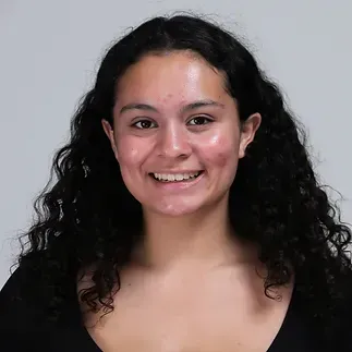 A young woman with curly hair is smiling for the camera.