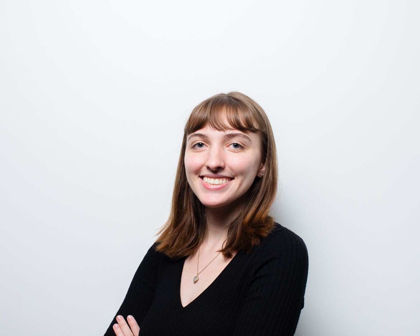 A woman in a black shirt is smiling with her arms crossed.