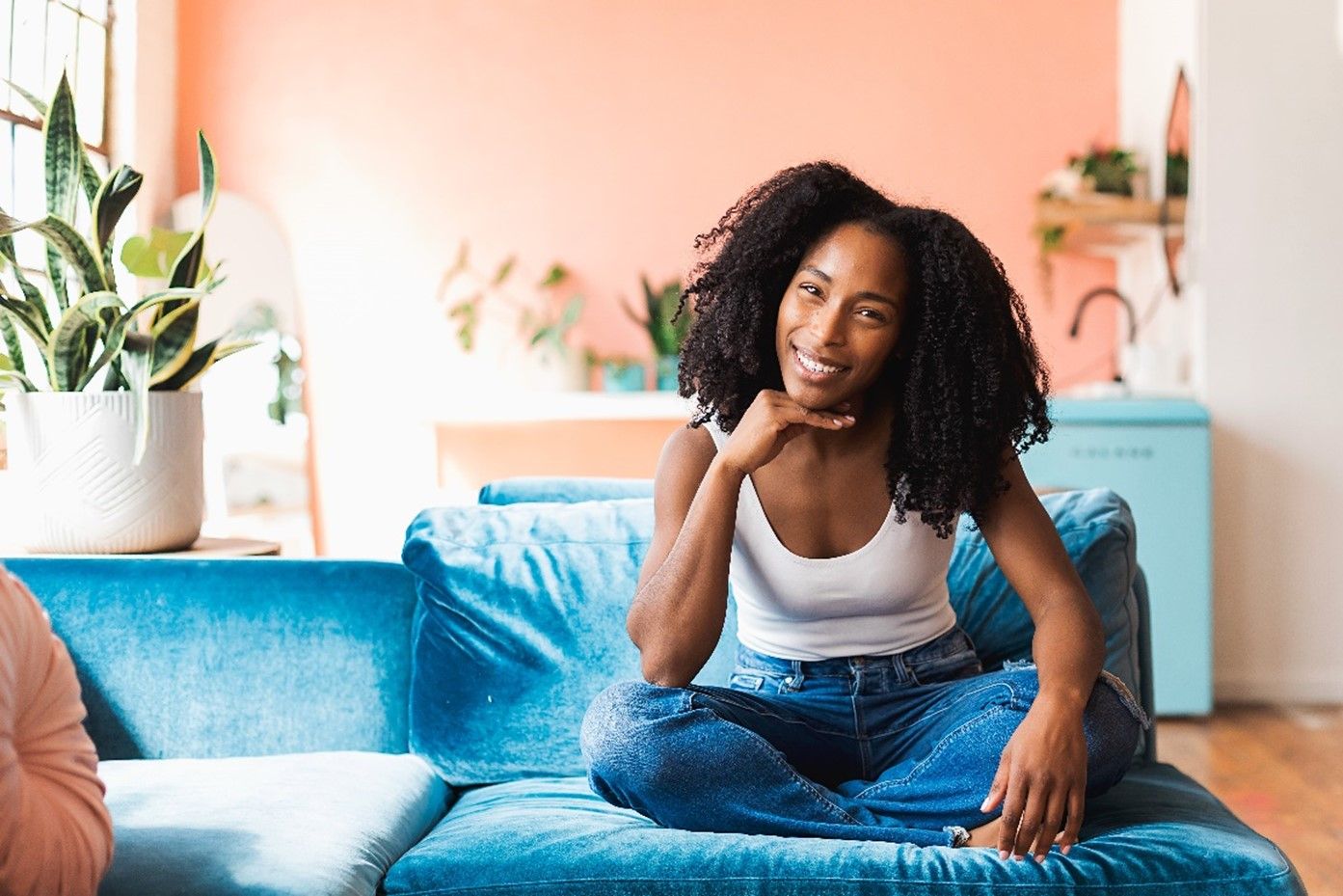 A woman is sitting on a blue couch in a living room.