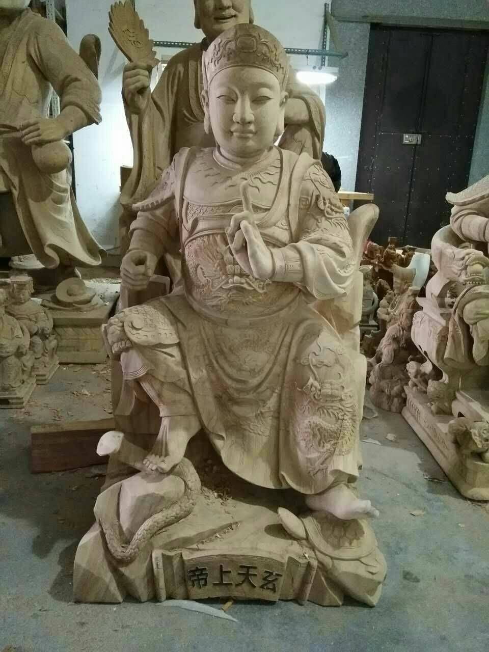 工作室裡一尊石雕神像，神像端坐，手持權杖，周圍環繞著其他雕塑。