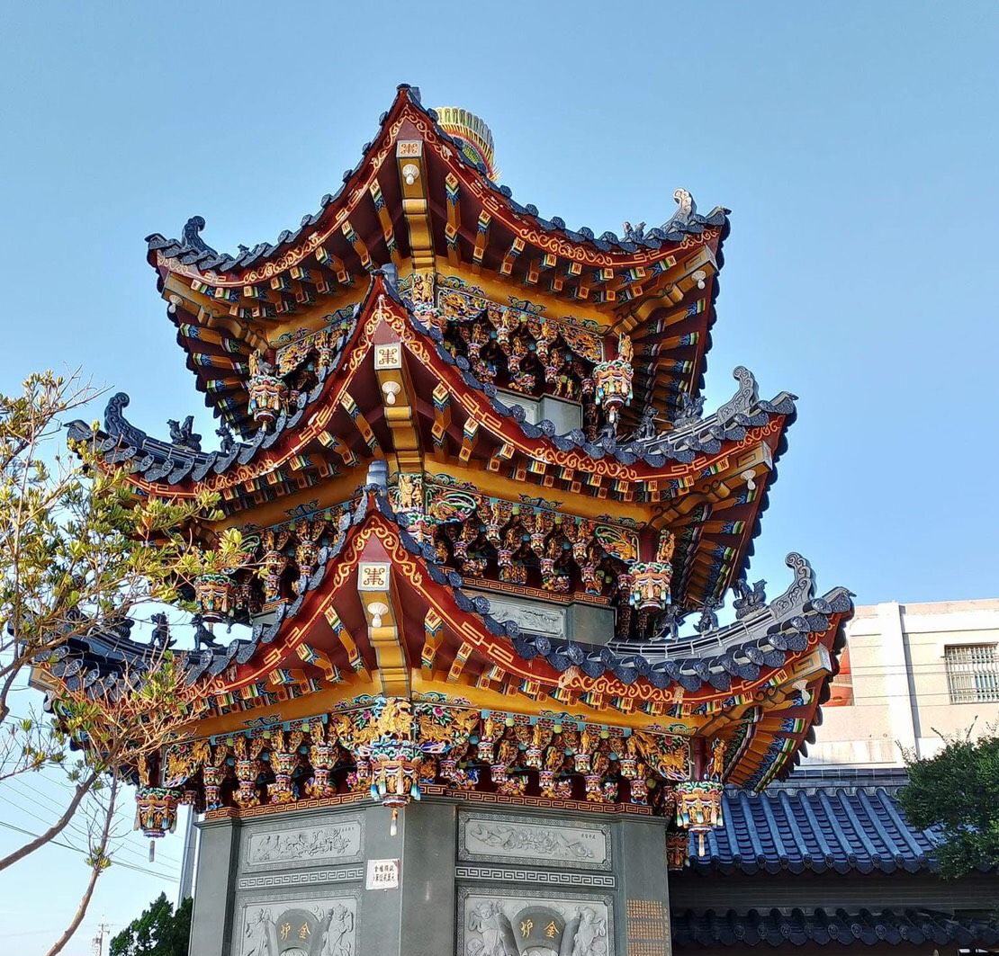 藍天映襯著雕刻精美的多層中國寺廟屋頂，色彩斑斕的雕刻細節栩栩如生。
