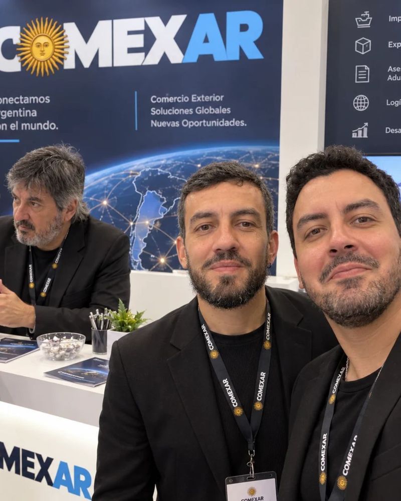 Integrantes da equipe ComexAR em um estande da empresa, com o painel da marca ao fundo