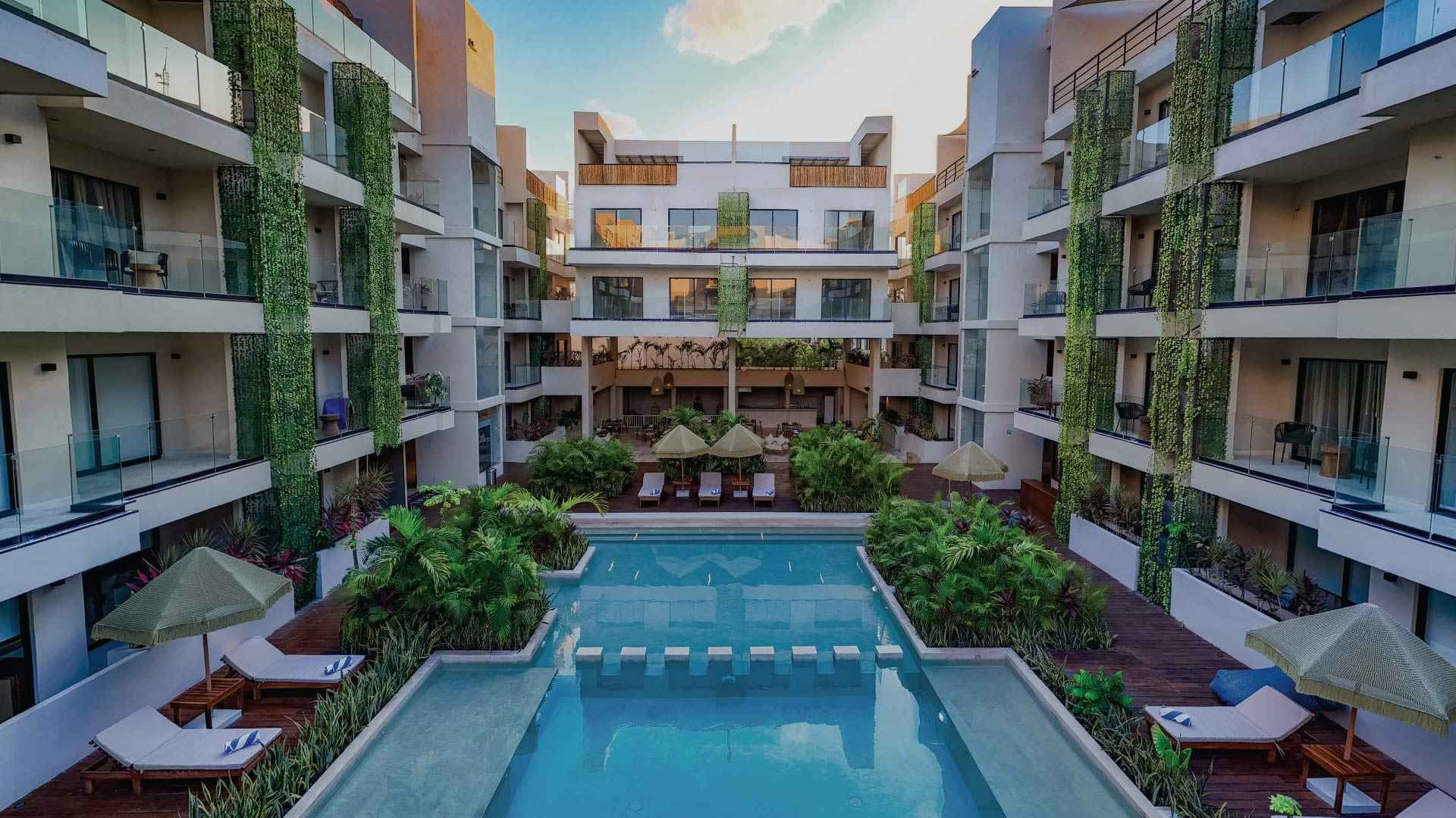Hay una gran piscina en el medio de un edificio. Hotel Bakal Tulum
