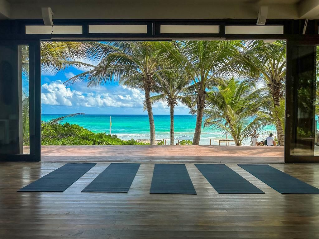 Una habitación con colchonetas de yoga en el suelo y vistas al océano.