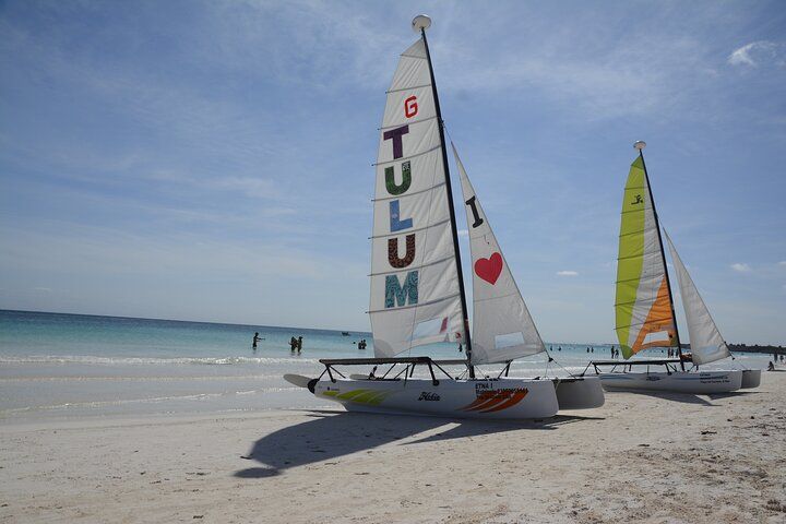 Dos veleros en una playa uno de los cuales dice "Amo Tulum"