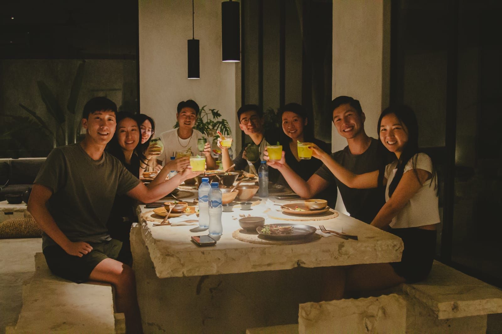 Un grupo de personas están sentadas en una mesa brindando con bebidas.