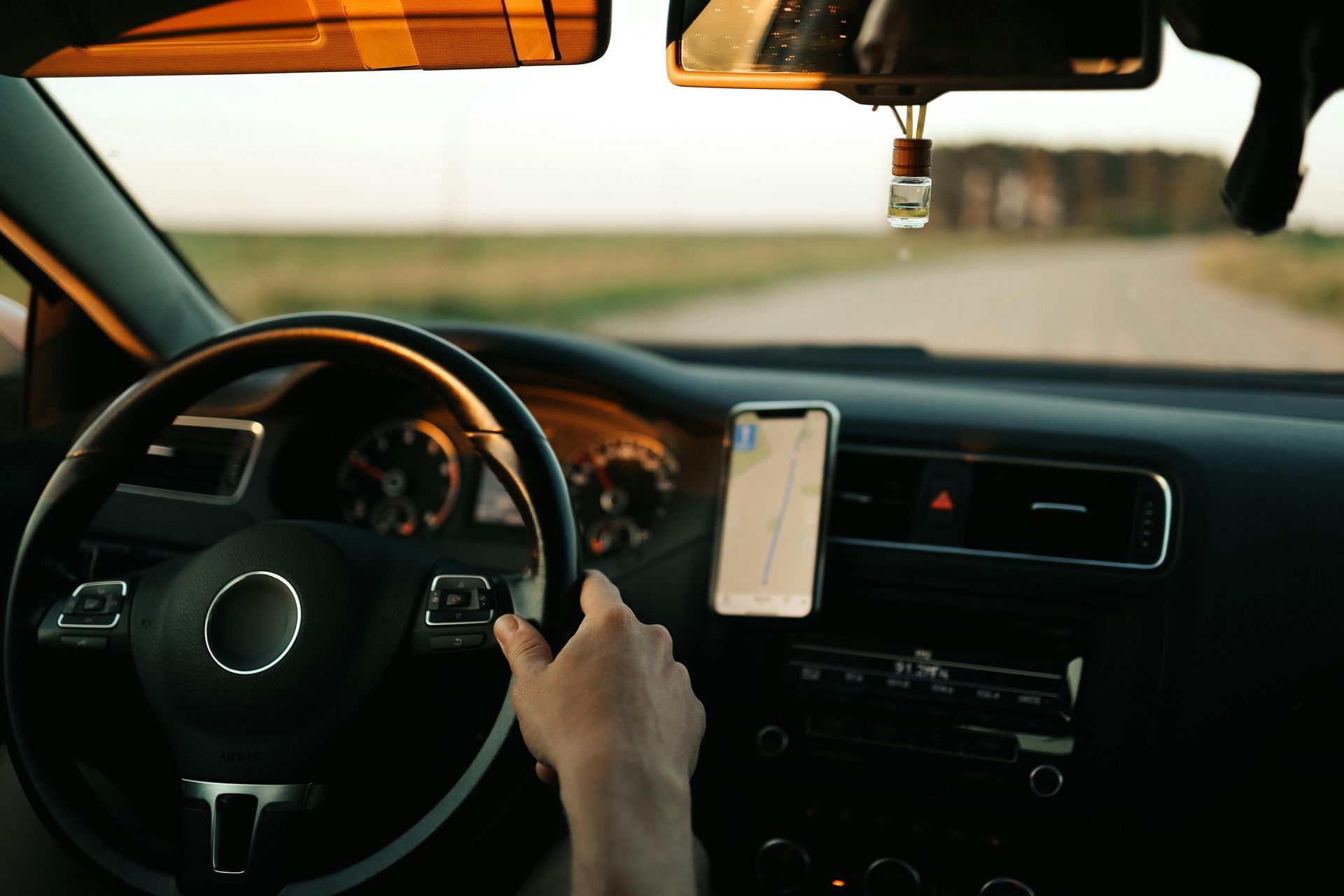 Una persona conduce un coche con un teléfono móvil en el volante.