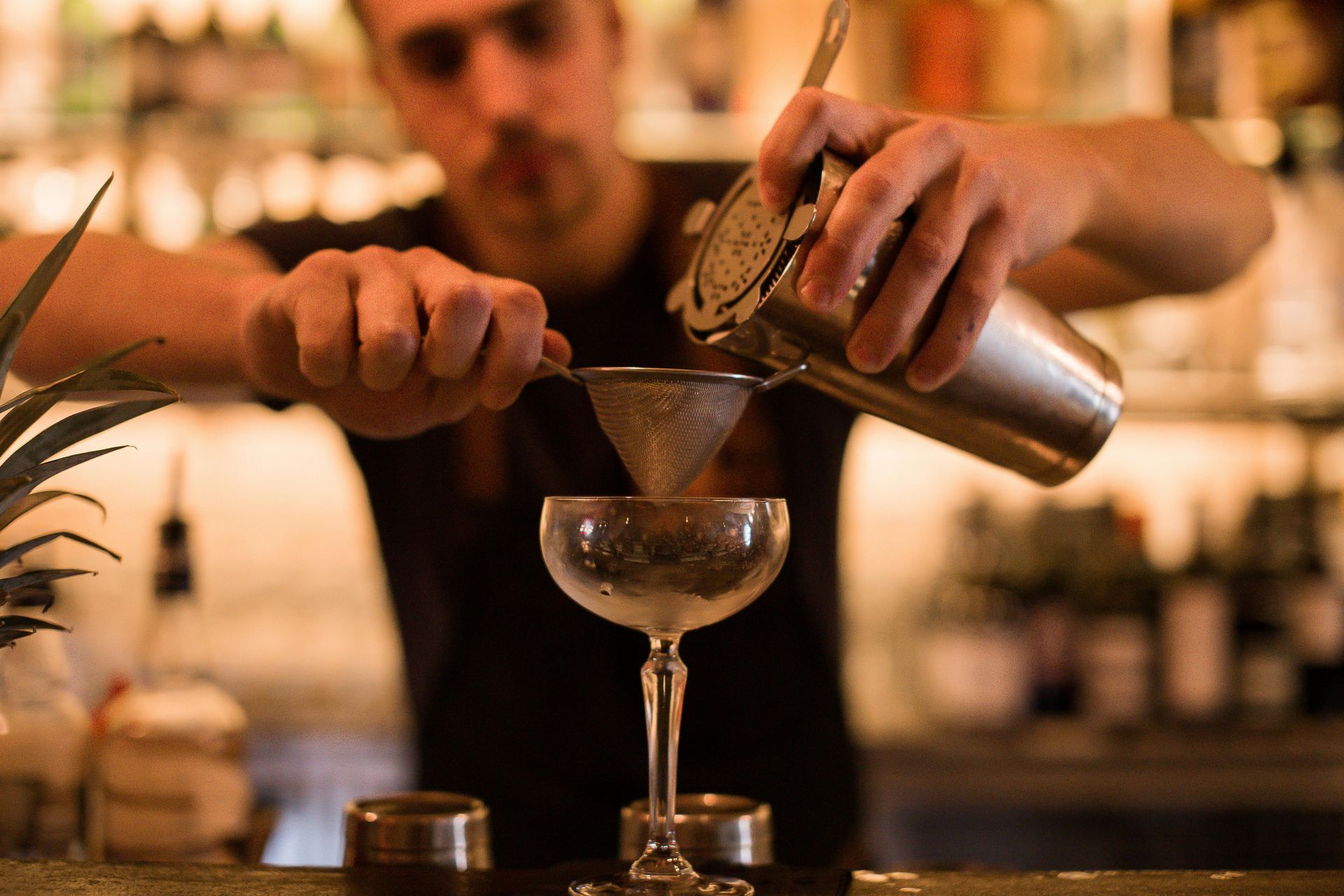 Un camarero está sirviendo una bebida en una copa de martini.